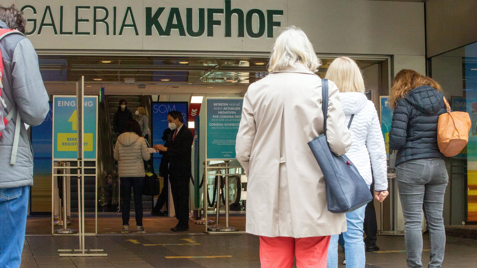 Menschen stehen vor einem Kaufhaus in München an: Für Geimpfte und von Covid-19 Genesene gelten künftig andere Regeln in Bayern.