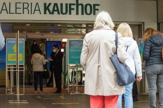 Menschen stehen vor einem Kaufhaus in München an: Für Geimpfte und von Covid-19 Genesene gelten künftig andere Regeln in Bayern.