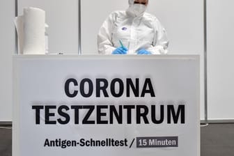 Eine Mitarbeiterin in Schutzkleidung steht im Corona-Testzentrum in der Messe Erfurt bereit.