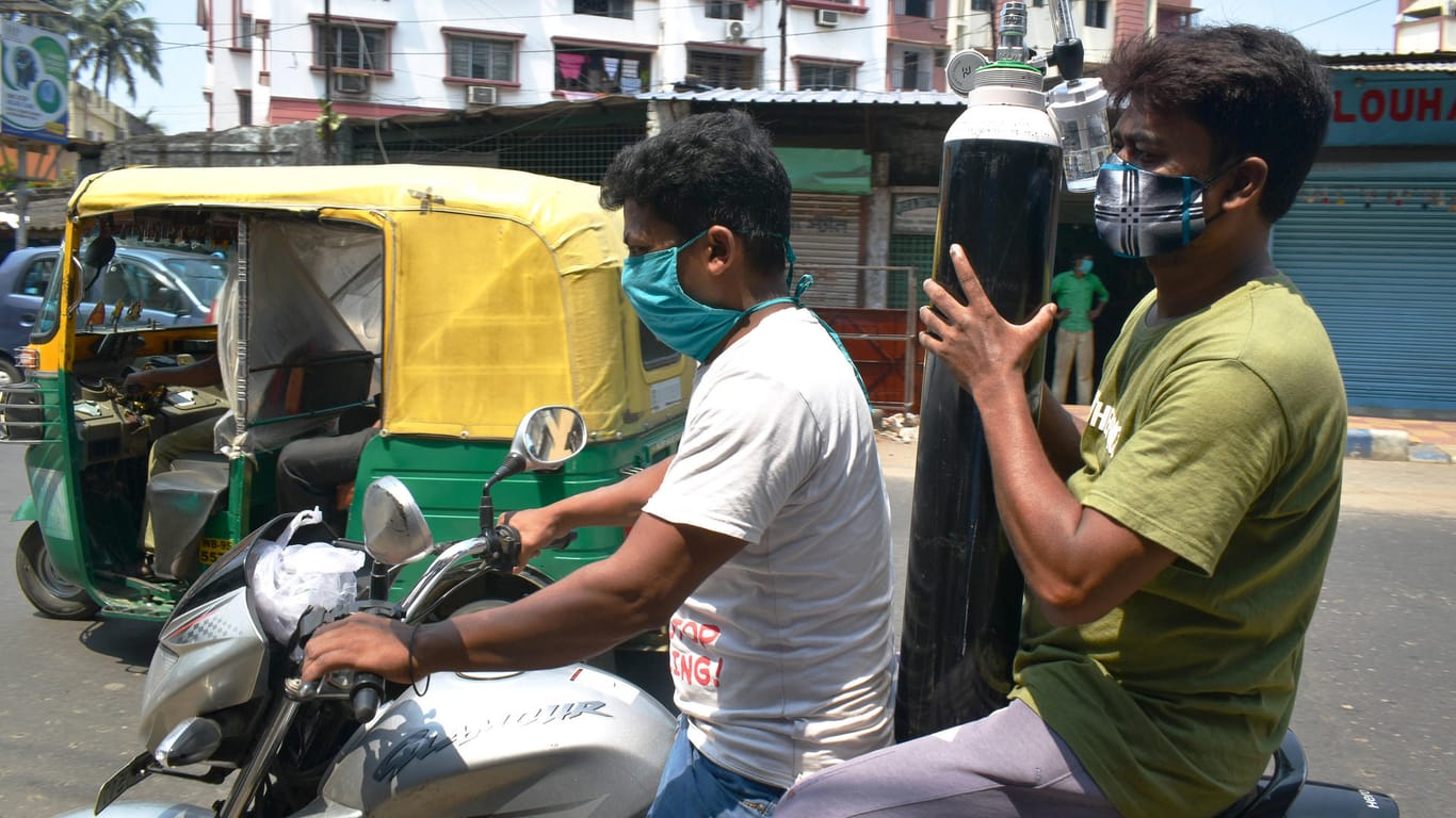 Zwei Männer transportieren eine Sauerstoffflasche: Viele Erkrankte werden Zuhause von ihren Familienangehörigen versorgt.