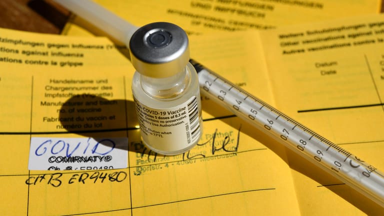 Ein gelber Impfausweis und Impfstoff (Symbolbild). Offenbar sind die Daten nicht digital erfasst worden.