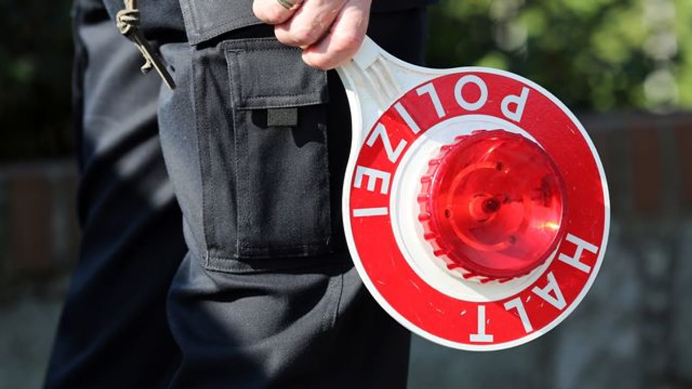 Ein Polizeibeamter hält eine Polizeikelle in der Hand (Symbolbild): Polizisten stellten bei einem 24-jährigen Autofahrer Drogen im Blut fest.