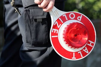 Ein Polizeibeamter hält eine Polizeikelle in der Hand (Symbolbild): Polizisten stellten bei einem 24-jährigen Autofahrer Drogen im Blut fest.