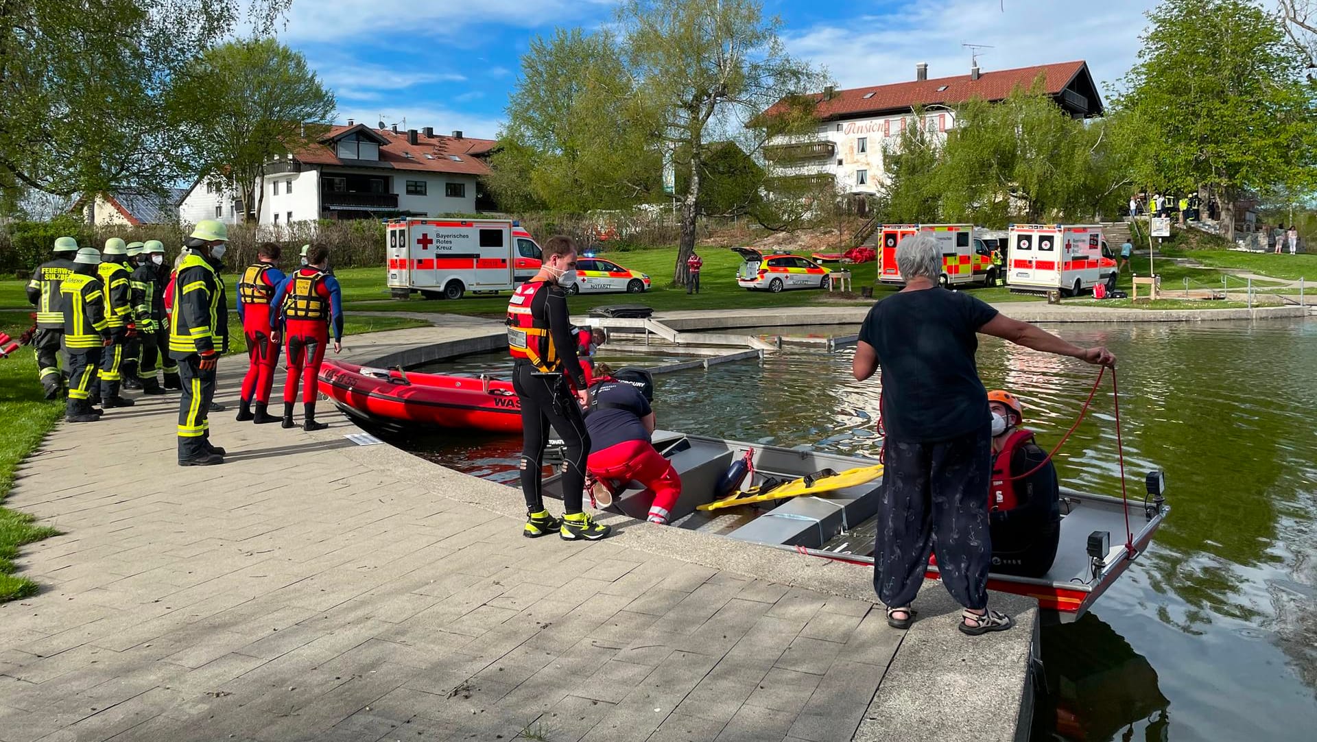 Einsatzkräfte der Feuerwehr und Rettungsdienste stehen an einem Badesee bei Sulzberg im Oberallgäu. Ein Kleinflugzeug mit vier Menschen an Bord ist kurz nach dem Start in den See gestürzt.