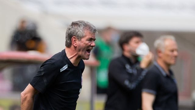 Kölns Trainer Friedhelm Funkel versucht seine Spieler auf dem Platz zu erreichen - im Hintergrund steht Freiburgs Trainer Christian Streich.