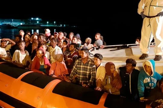 Flüchtlinge bereiten sich darauf vor, bei ihrer Ankunft im Hafen von Lampedusa aus einem Beiboot zu steigen (Archiv).