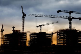 Silhouetten von Kränen auf einer Baustelle: Eine Berliner Bürgerinitiative will Immobilienunternehmen mit Schuldverschreibungen entschädigen.