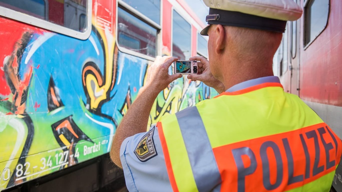 Ein Polizist fotografiert einen mit Graffiti beschmierten Zug (Symbolbild): In Bielefeld ist ein Sprayer festgenommen worden.