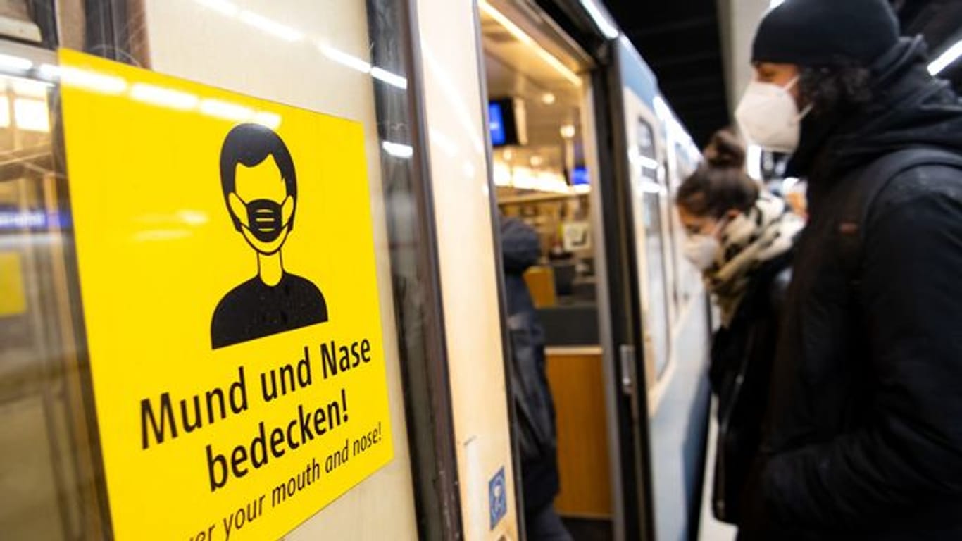 Ein Mann und eine Frau mit FFP2-Masken steigen in eine U-Bahn.