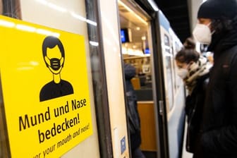 Ein Mann und eine Frau mit FFP2-Masken steigen in eine U-Bahn.