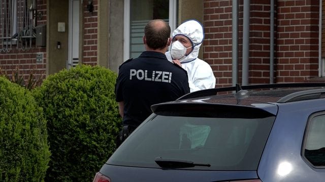 Ein Mitarbeiter der Spurensicherung und ein Polizist vor dem Haus, in dem eine Leiche gefunden wurde: Der mutmaßliche Täter ging selbst zur Polizei.