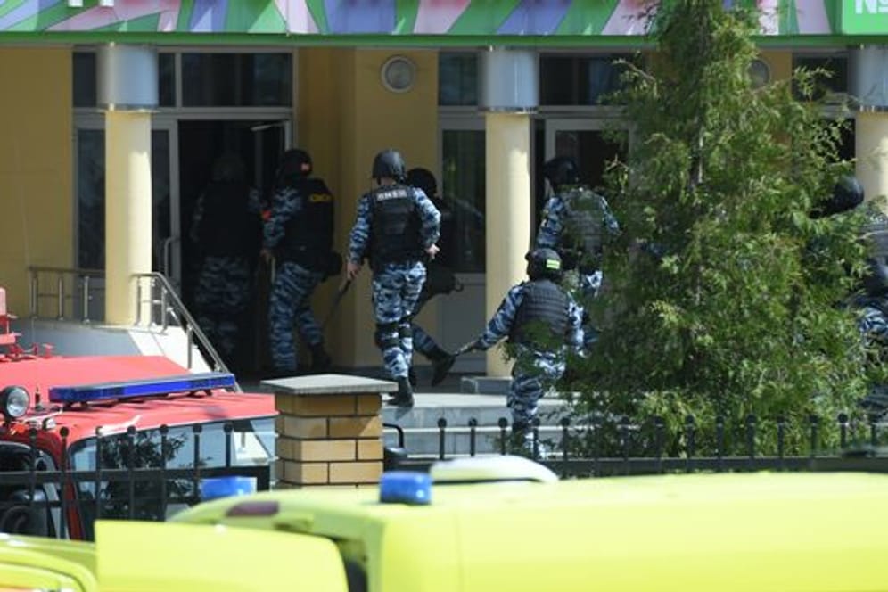 Rettungswagen und Polizeifahrzeuge mit Blaulicht und Sirene: der Tatort in der russischen Stadt Kasan nach dem tödlichen Angriff.