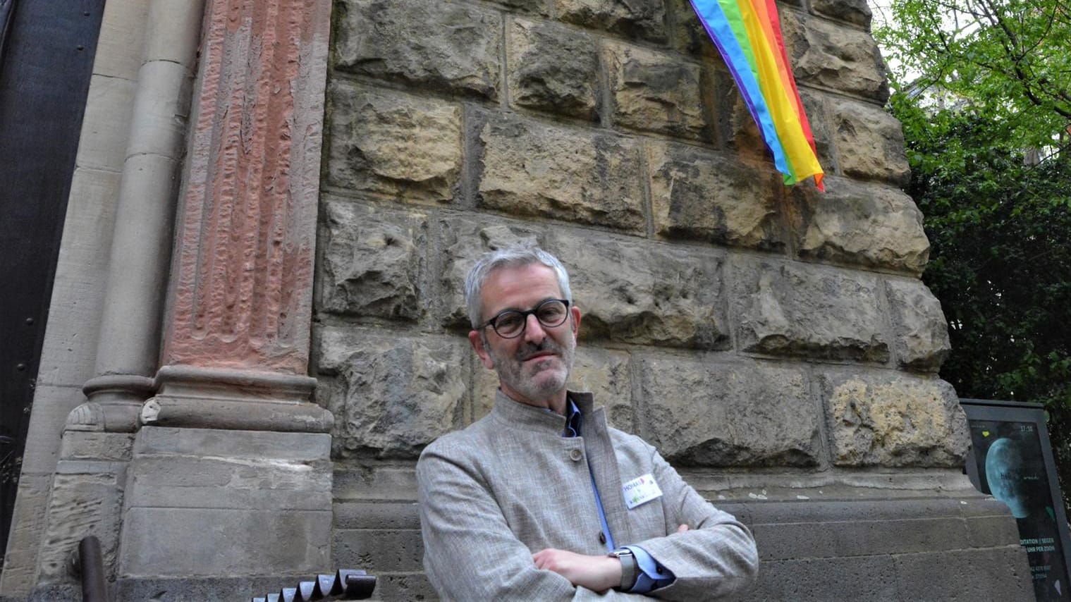 Pfarrer Thomas Frings vor der Regenbogenflagge an St. Michael.