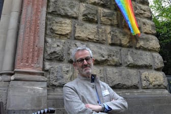 Pfarrer Thomas Frings vor der Regenbogenflagge an St. Michael.