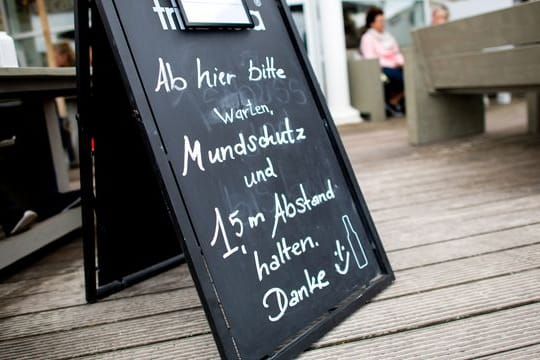 "Mundschutz und 1,5 m Abstand halten" steht auf einem Schild vor einem Lokal auf der Nordseeinsel Norderney.