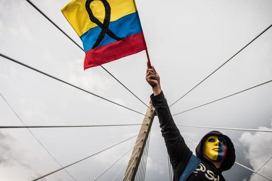 Ein maskierter Demonstrant schwenkt die kolumbianische Flagge.
