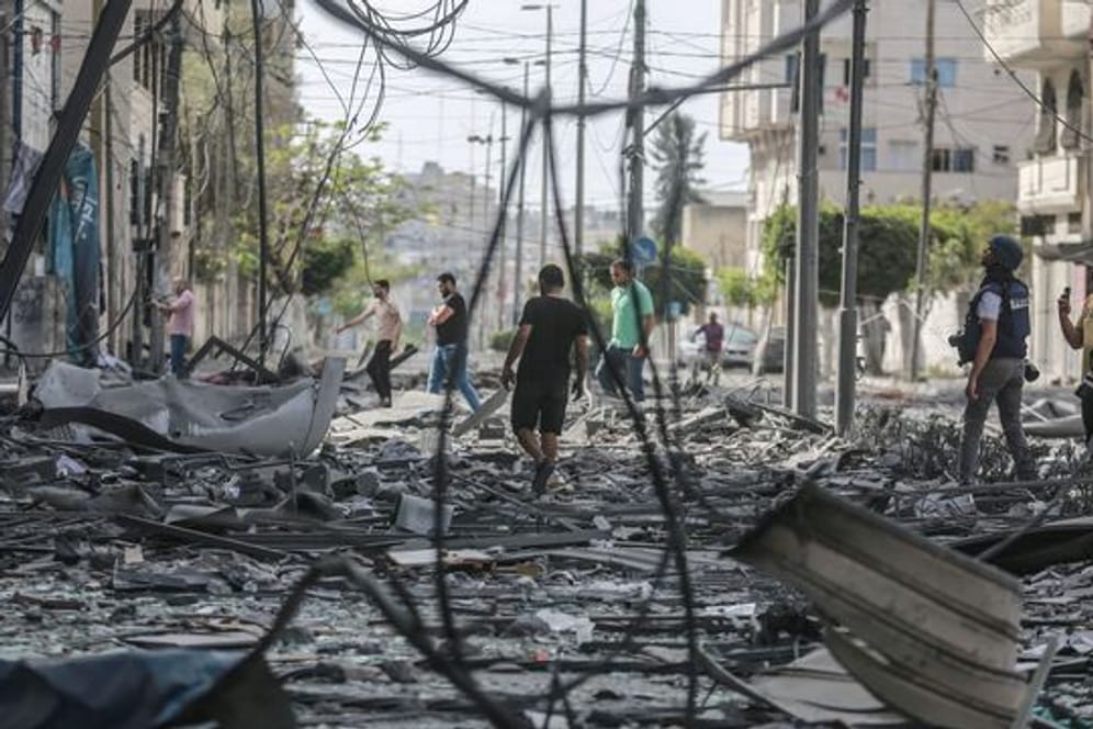 Palästinenser inspizieren das Umfeld des schwer beschädigten Al-Jawhara-Turm, nachdem der Turm von israelischen Luftangriffen getroffen worden war.