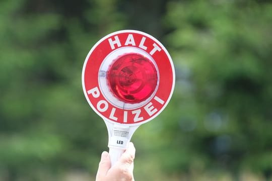 Eine Polizistin hält eine rote Winkerkelle in die Höhe (Symbolbild): Der Mann wollte die Beamten von der Echtheit des Führerscheins überzeugen.