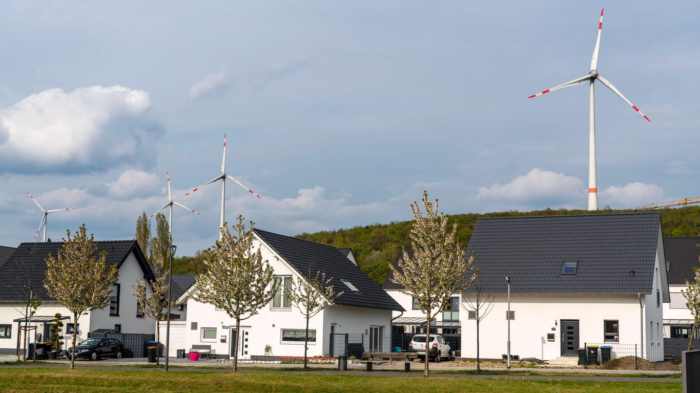 Häuser mit Windanlagen im Hintergrund: Die Energiewende ist zentraler Baustein der Klimapolitik in Deutschland.