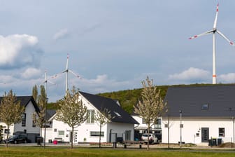 Häuser mit Windanlagen im Hintergrund: Die Energiewende ist zentraler Baustein der Klimapolitik in Deutschland.