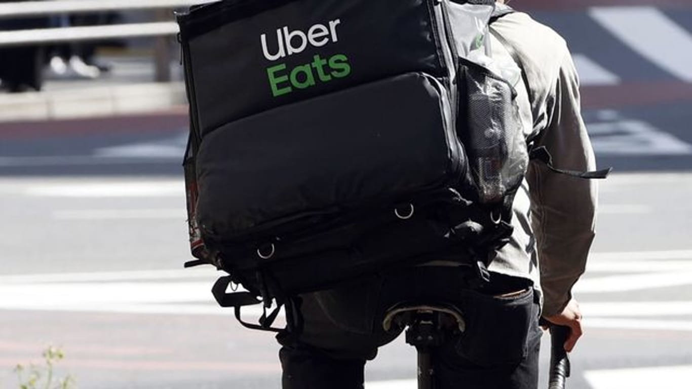 Ein Mitarbeiter des Essenslieferdienstes Uber Eats radelt mit einer Lieferung durch die Stadt.