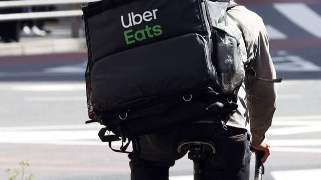 Ein Mitarbeiter des Essenslieferdienstes Uber Eats radelt mit einer Lieferung durch die Stadt. Ein Mitarbeiter des Essenslieferdienstes Uber Eats radelt mit einer Lieferung durch die Stadt.
