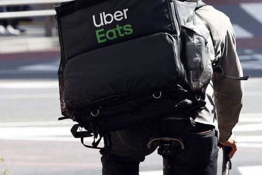 Ein Mitarbeiter des Essenslieferdienstes Uber Eats radelt mit einer Lieferung durch die Stadt.