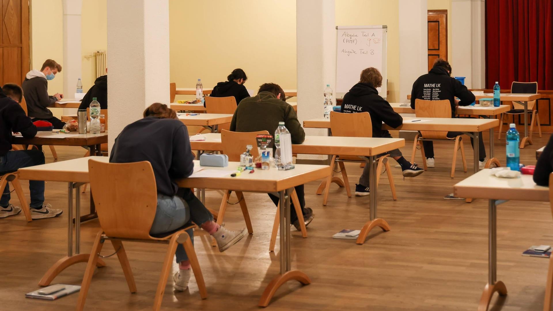 Schüler und Schülerinnen sitzn in der Aula einer Schule und schreiben eine Abiturklausur (Symbolbild): Weil eine Lehrerin die Klausur versehentlich 20 Minuten zu früh eingesammelt hat, dürfen die Schüler die Klausur nun wiederholen.