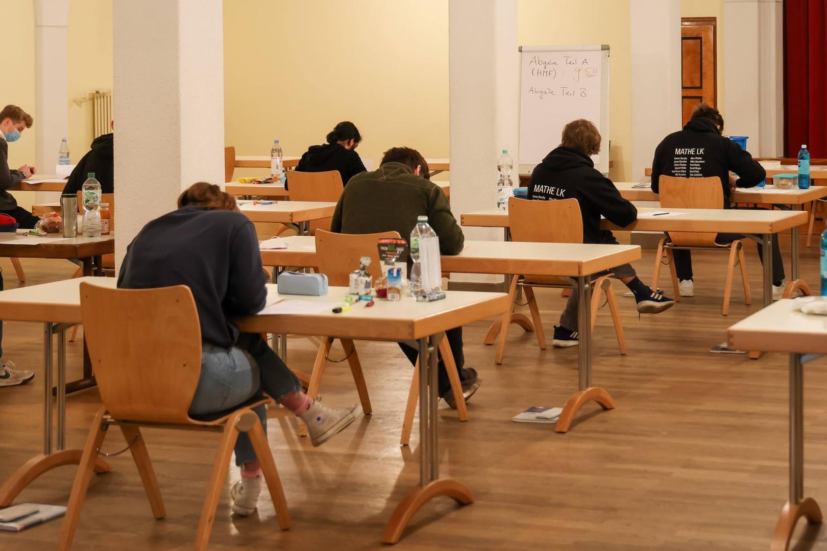 Schüler und Schülerinnen sitzn in der Aula einer Schule und schreiben eine Abiturklausur (Symbolbild): Weil eine Lehrerin die Klausur versehentlich 20 Minuten zu früh eingesammelt hat, dürfen die Schüler die Klausur nun wiederholen.