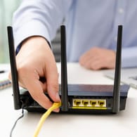 Ein Router wird mit dem Kabel verbunden: Ein Sicherheitsforscher hat Schwachstellen im WLAN-Protokoll gefunden.