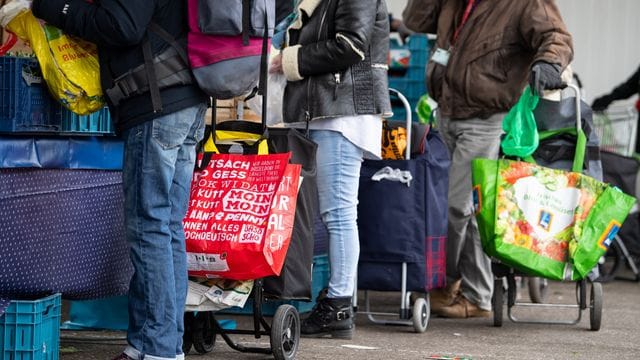 Gäste der Münchner Tafel stehen an der Ausgabestelle am Großmarkt.
