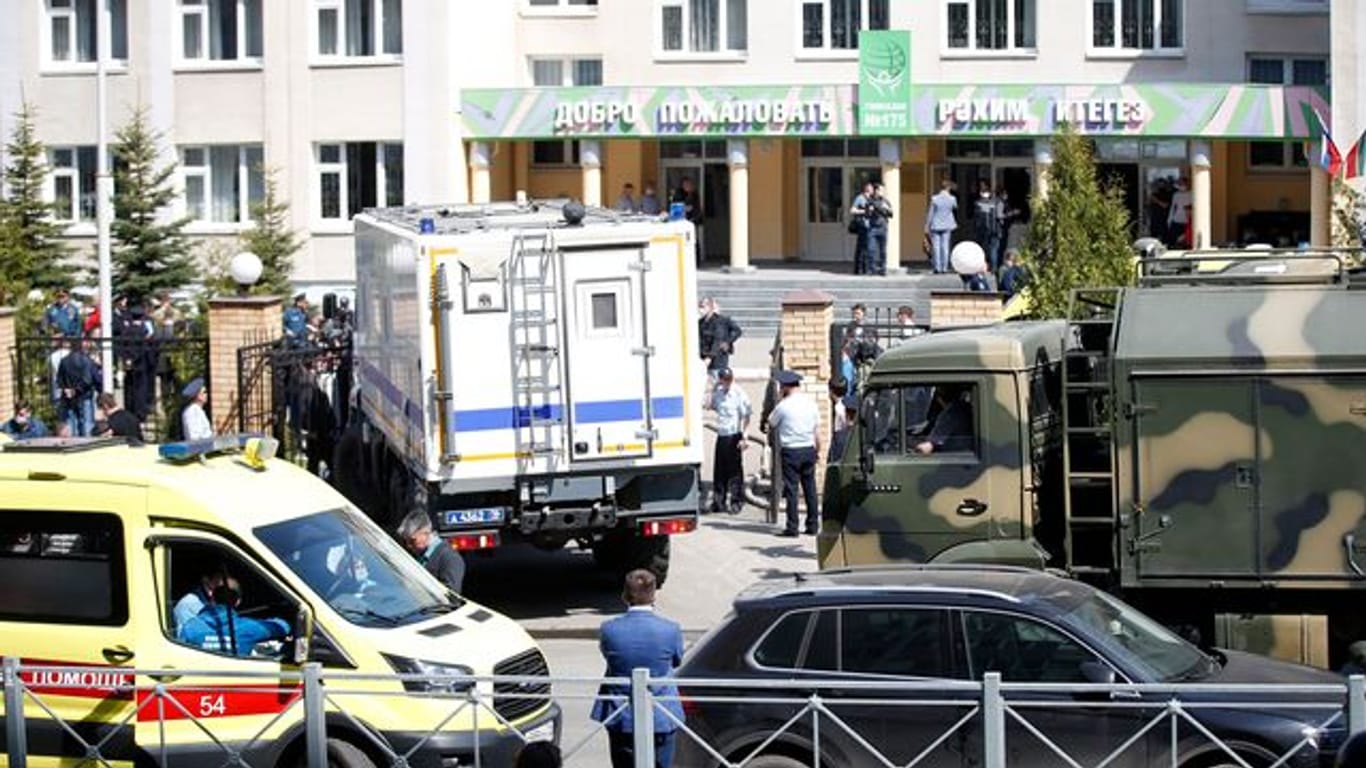 Ein Krankenwagen und Polizeifahrzeuge stehen nach einem Angriff mit Schusswaffen vor einer russischen Schule in Kasan.