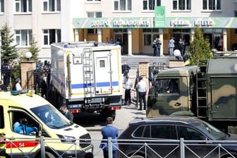Ein Krankenwagen und Polizeifahrzeuge stehen nach einem Angriff mit Schusswaffen vor einer russischen Schule in Kasan.
