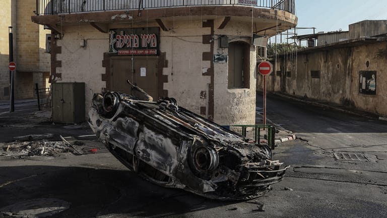 Lod: Ein verbranntes Auto liegt nach Raketenangriffen mit dem Dach auf einer Straße.
