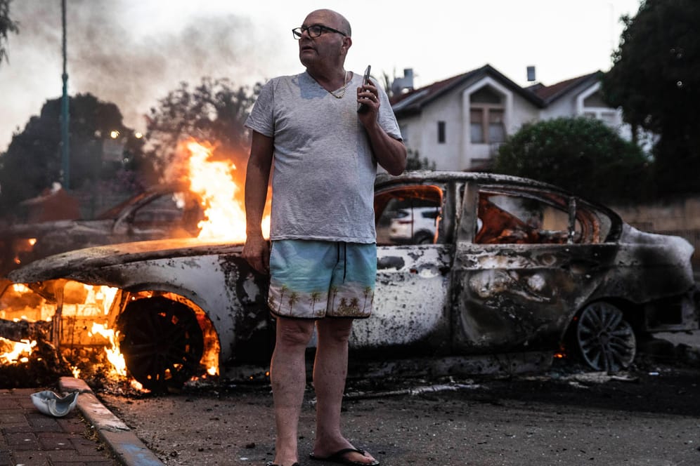 Lod: Ein Mann steht während gewaltsamer Proteste bei seinem brennenden Auto.