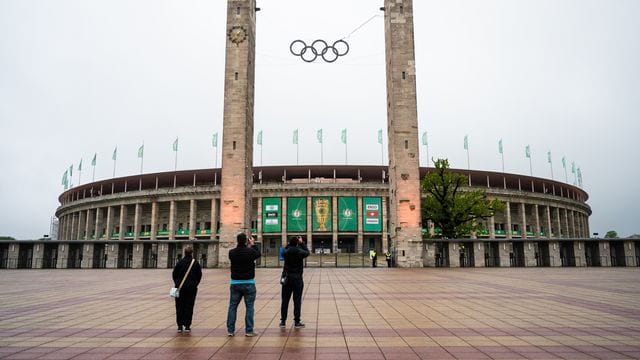 Drei Fußball-Fans stehen vor dem Olympiastadion und machen Fotos. Drei Fußball-Fans stehen vor dem Olympiastadion und machen Fotos.