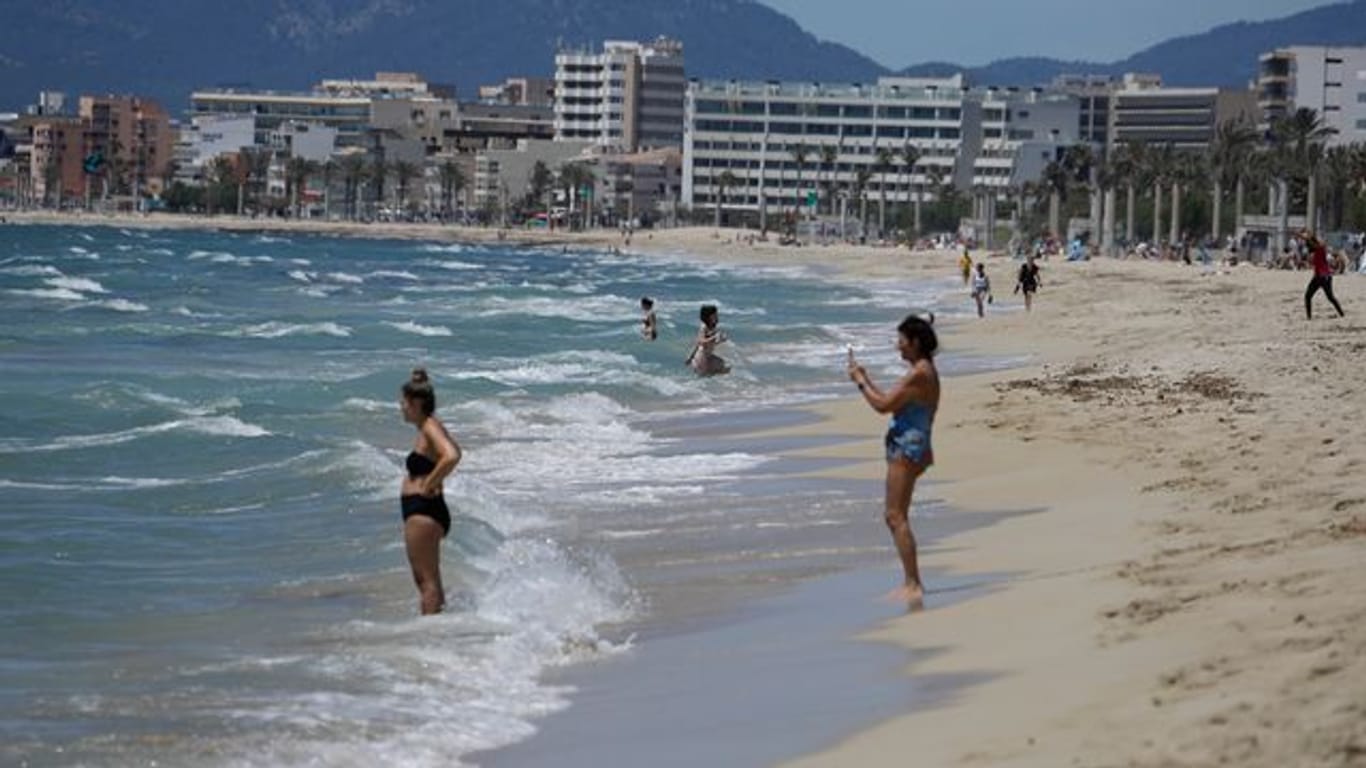 Menschen gehen am Strand von Arenal schwimmen.