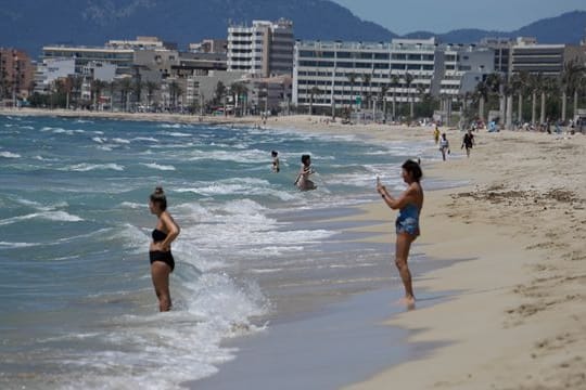 Menschen gehen am Strand von Arenal schwimmen.