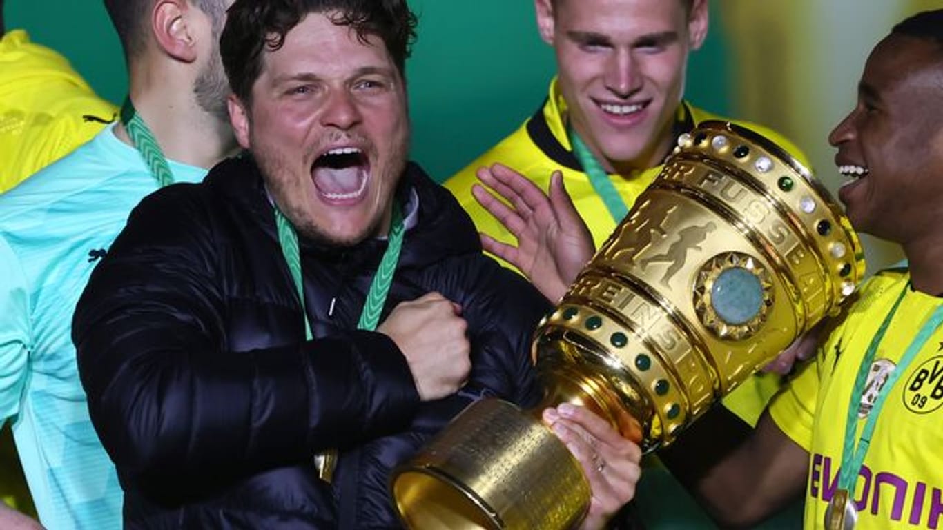 Edin Terzic (M), Dortmunds Cheftrainer, hält den Pokal im Arm