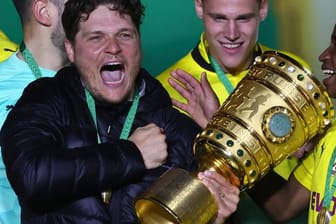 Edin Terzic (M), Dortmunds Cheftrainer, hält den Pokal im Arm