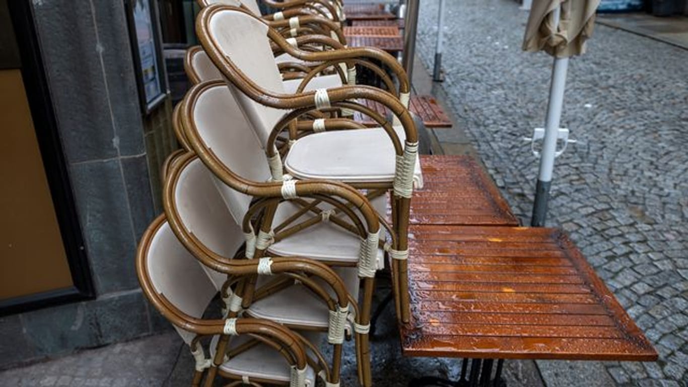 Tische und Stühle eines Cafés stehen auf einem Gehweg