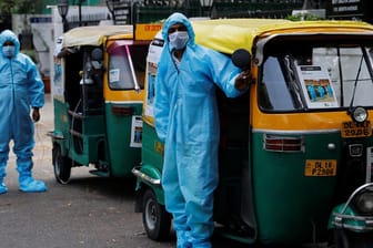 Fahrer von Rikscha-Krankenwagen in Schutzanzügen und mit Mund-Nasenschutz: Sie fahren Corona-Patienten gratis durch die indische Hauptstadt Neu Delhi.