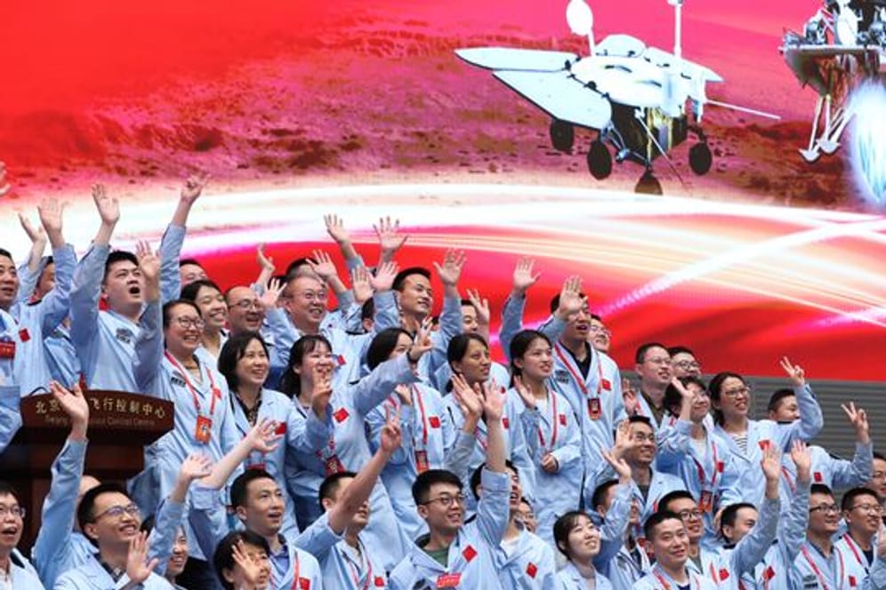 Technisches Personal im Pekinger Raumfahrtkontrollzentrum feiert die erfolgreiche Landung der chinesischen Sonde Tianwen-1 auf dem Mars.