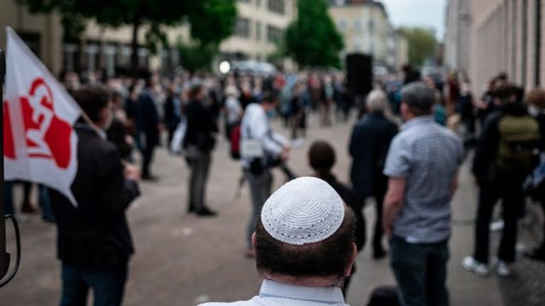 Menschen stehen bei einer Solidaritätskundgebung in Gelsenkirchen auf dem Platz vor der Synagoge.