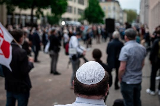 Menschen stehen bei einer Solidaritätskundgebung in Gelsenkirchen auf dem Platz vor der Synagoge.