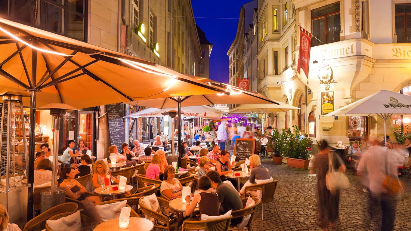 Menschen sitzen in den Abendstunden in einem Straßencafé in Leipzig (Archivbild): Die Außengastronomie in der Stadt ist neuerdings wieder geöffnet.