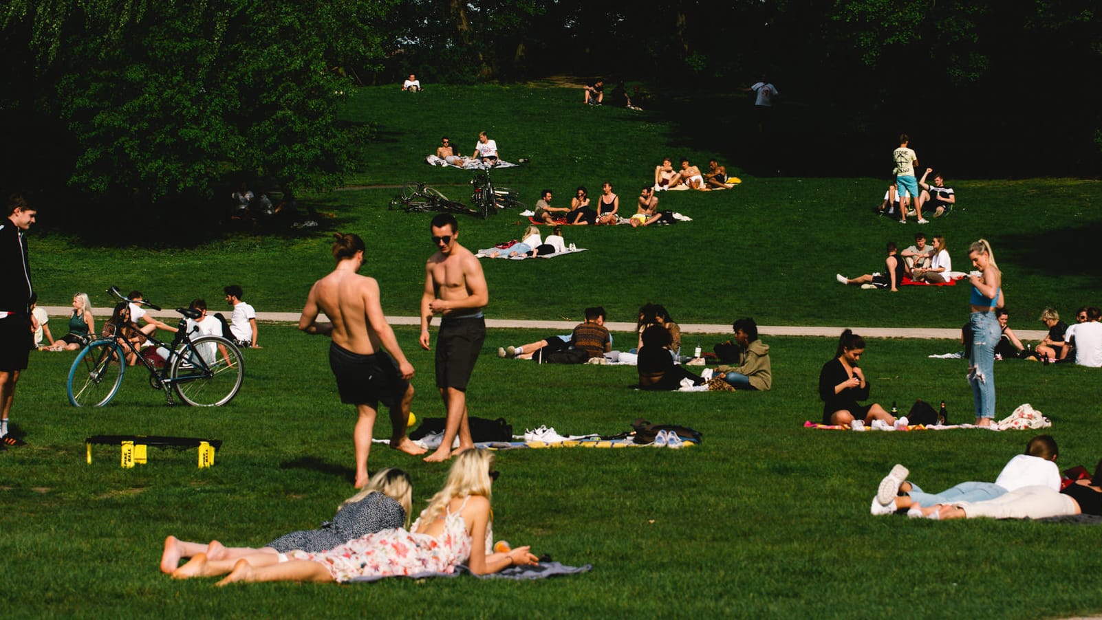 Menschen liegen in Köln auf einer Wiese (Archivbild): Wer gegen Corona durchgeimpft ist, darf sich mit anderen Durchgeimpften treffen. Für den Rest gelten Kontaktbeschränkungen.