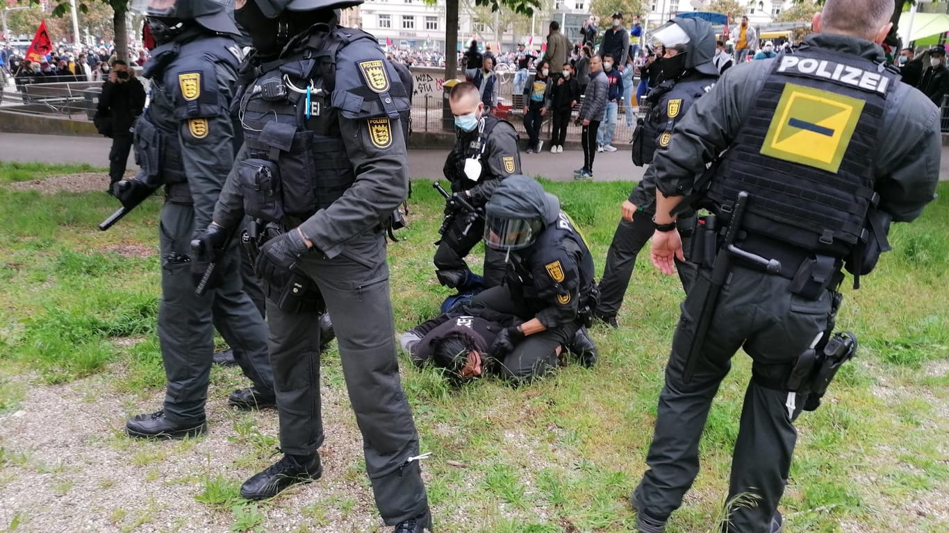 Polizisten halten bei einer pro-palästinensische Demonstration auf dem Marienplatz eine Person am Boden fest und schirmen sie gegen andere Demonstranten ab.