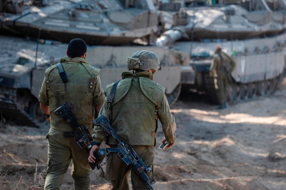 Israel, Sderot: Soldaten der israelischen Verteidigungsstreitkräfte (IDF) nehmen ihre Position neben israelischen Panzern an der Grenze von Israel und Gaza ein.