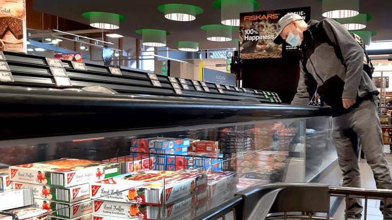 Ein Mann steht an der Tiefkühltheke eines Supermarkts: Die Preise für Produkte wie Fertigpizza könnten bald steigen.